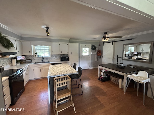 kitchen with a sink, backsplash, black appliances, and wood finished floors