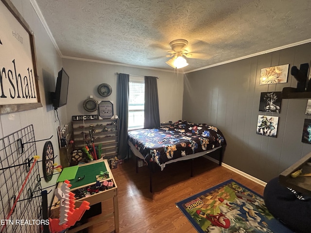 bedroom featuring a ceiling fan, a textured ceiling, ornamental molding, and wood finished floors