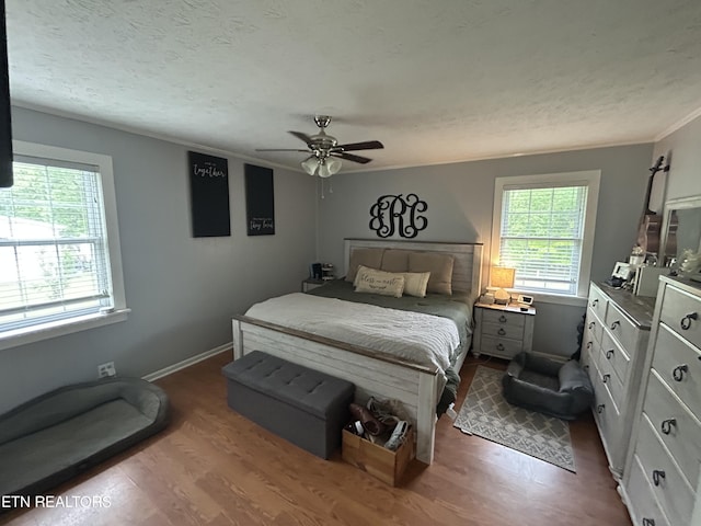 bedroom featuring crown molding, baseboards, ceiling fan, and dark wood-type flooring