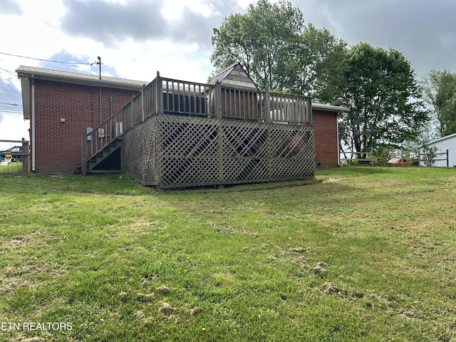 rear view of house featuring a lawn, brick siding, stairway, and a wooden deck