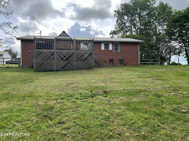 rear view of house featuring brick siding, fence, and a yard