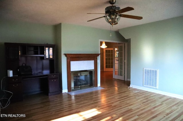 unfurnished living room featuring visible vents, a glass covered fireplace, wood finished floors, baseboards, and ceiling fan