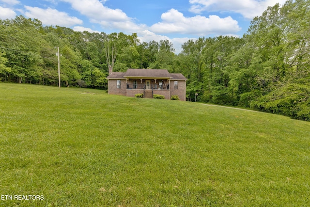243 Bunch Ln, Clinton, TN 37716 - view of front of property with a front yard, brick siding, a wooded view, and covered porch