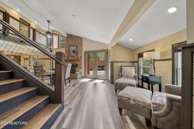 living area with lofted ceiling with beams, wainscoting, french doors, wood finished floors, and stairway