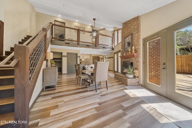 interior space with ceiling fan, a high ceiling, a fireplace, wood finished floors, and stairway