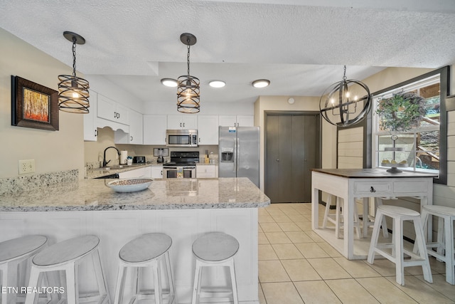 kitchen with a peninsula, a textured ceiling, appliances with stainless steel finishes, and a sink