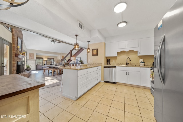 kitchen with a sink, stainless steel appliances, a ceiling fan, open floor plan, and a peninsula