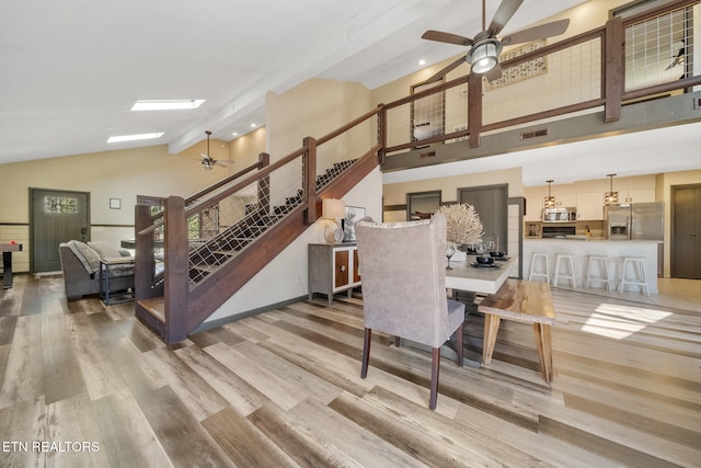 dining space with stairway, high vaulted ceiling, ceiling fan, and light wood-style flooring