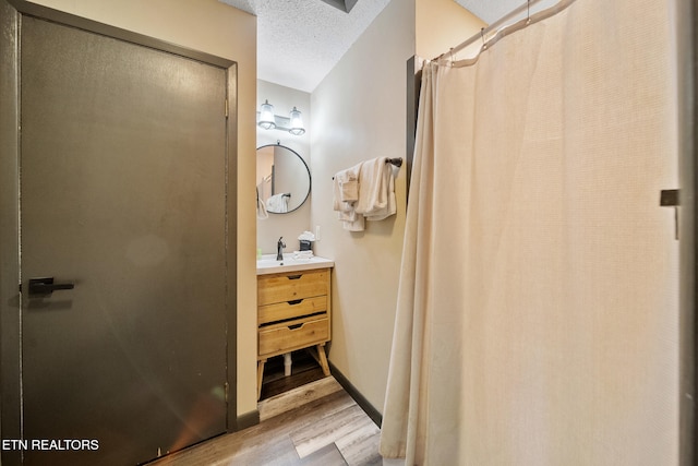bathroom with a textured ceiling, a shower stall, wood finished floors, and vanity