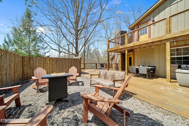 exterior space featuring fence, a wooden deck, outdoor dining space, and an outdoor fire pit