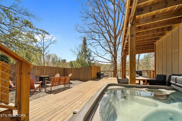 deck featuring a hot tub and fence