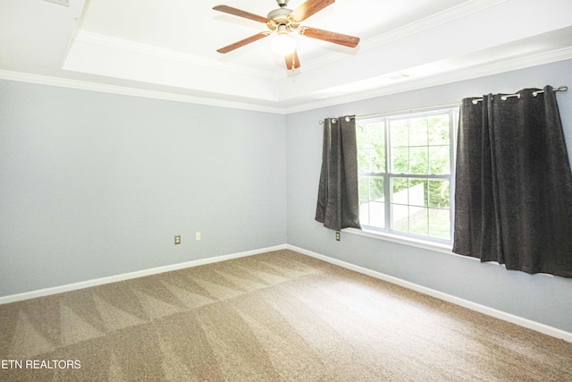 carpeted spare room with a ceiling fan, baseboards, ornamental molding, visible vents, and a raised ceiling