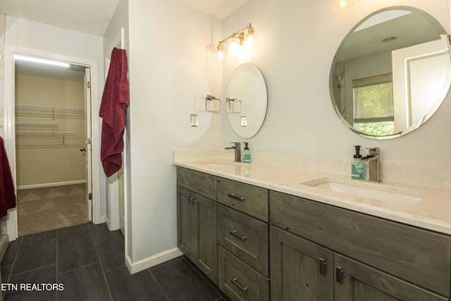 full bathroom featuring tile patterned floors, double vanity, a walk in closet, and a sink