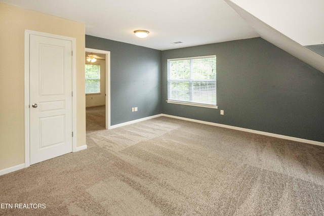 additional living space with carpet flooring, vaulted ceiling, baseboards, and visible vents