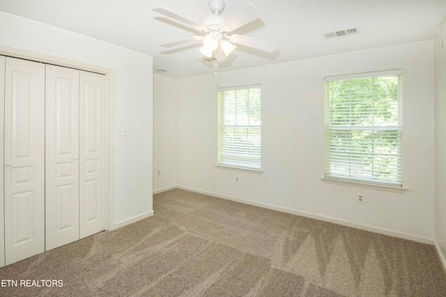unfurnished bedroom with a closet, visible vents, multiple windows, and carpet floors