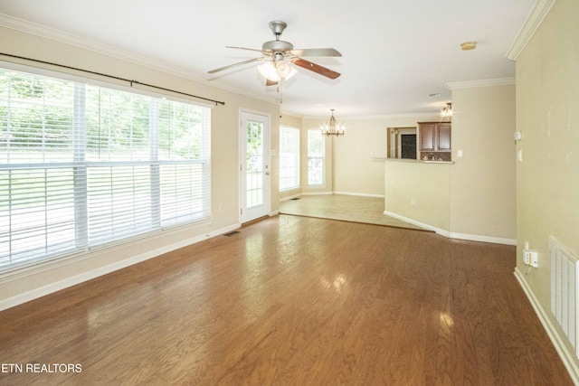 spare room with ceiling fan with notable chandelier, wood finished floors, ornamental molding, visible vents, and baseboards