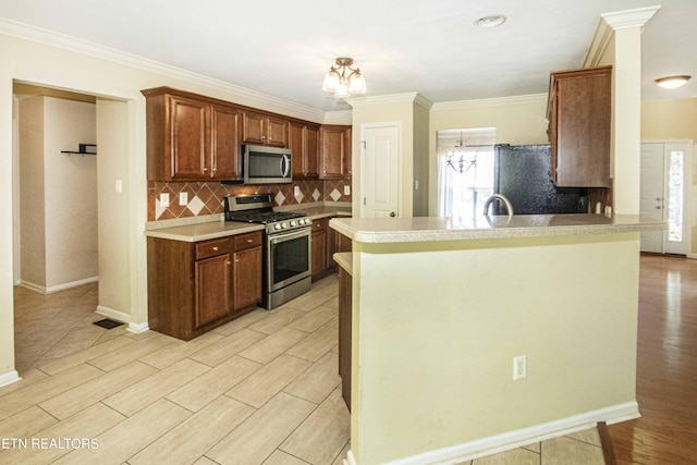 kitchen featuring light wood-type flooring, decorative backsplash, light countertops, a notable chandelier, and appliances with stainless steel finishes