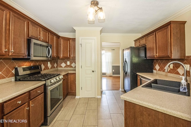 kitchen featuring a sink, ornamental molding, light countertops, and appliances with stainless steel finishes