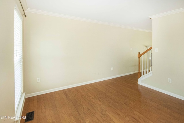 unfurnished room featuring ornamental molding, stairs, visible vents, and wood finished floors