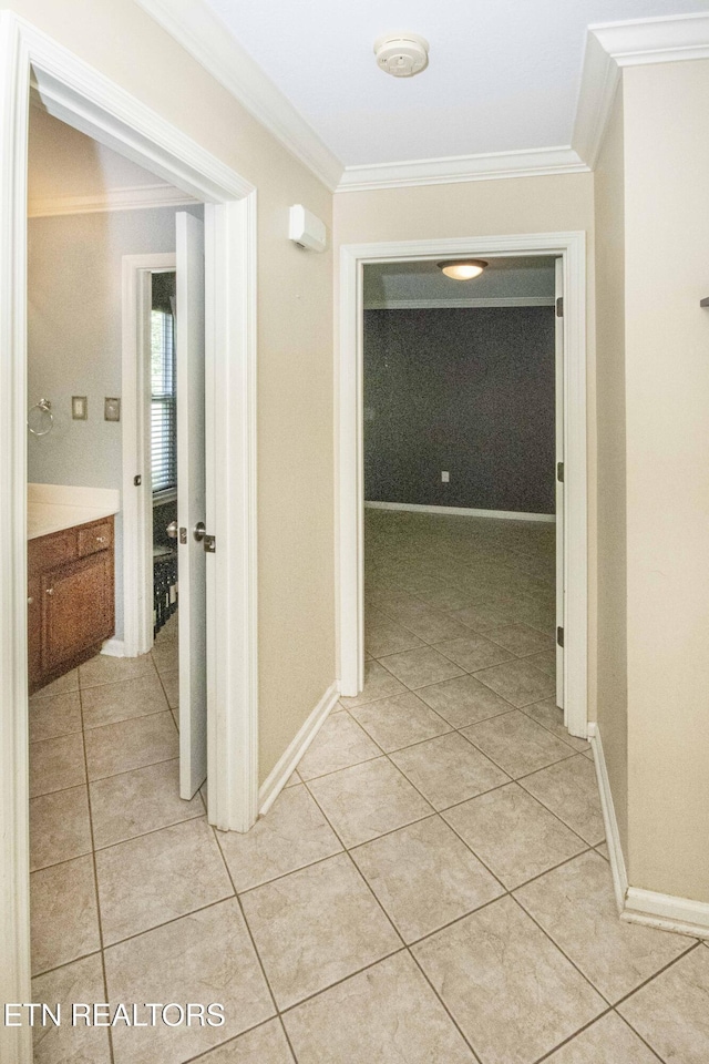 hall featuring light tile patterned floors, baseboards, and ornamental molding