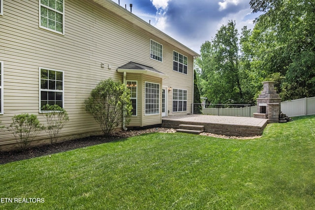 back of house with a yard, a patio area, exterior fireplace, and fence
