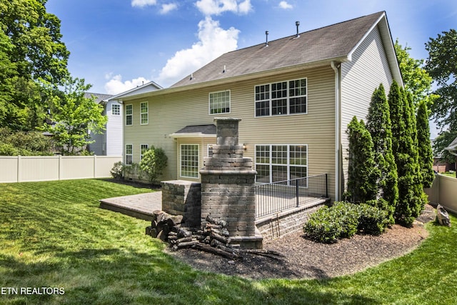rear view of house featuring a yard and fence