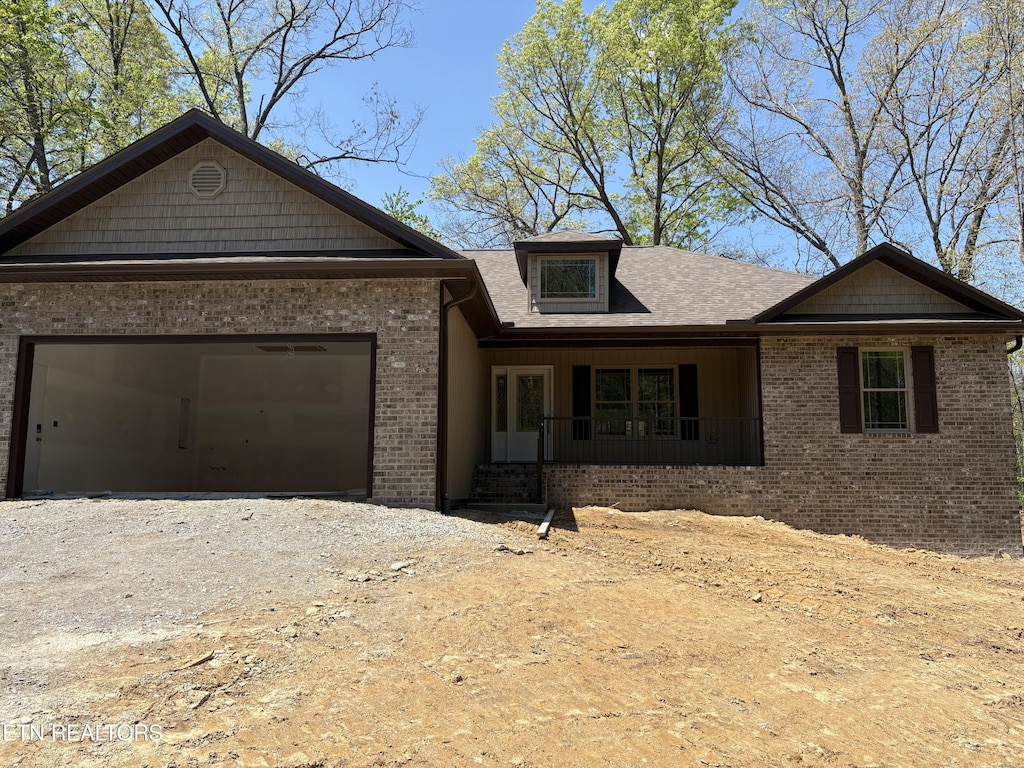 686 Westchester Dr, Crossville, TN 38558 - single story home featuring a garage, brick siding, dirt driveway, a shingled roof, and a porch