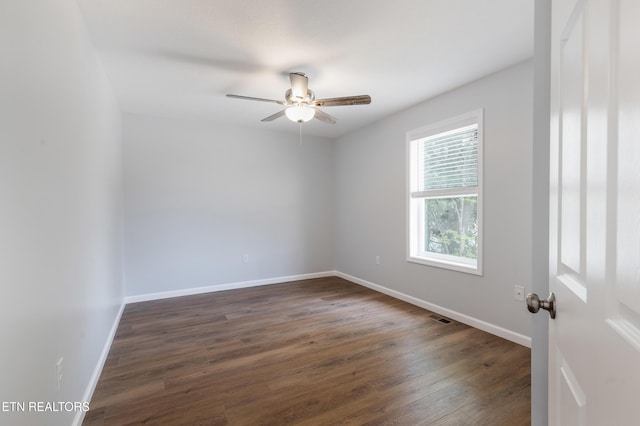 spare room featuring baseboards, ceiling fan, dark wood-style floors, and visible vents