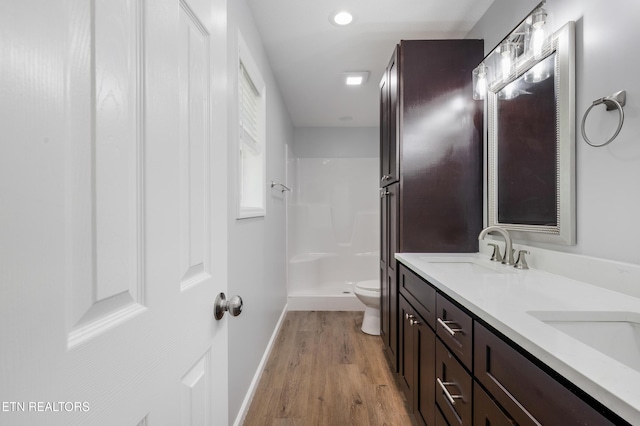 bathroom with a sink, toilet, baseboards, wood finished floors, and a shower