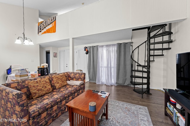 living area with a high ceiling, wood finished floors, a notable chandelier, and stairway