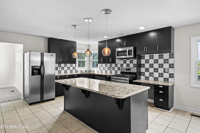 kitchen featuring a breakfast bar area, a kitchen island, a sink, dark cabinetry, and stainless steel appliances