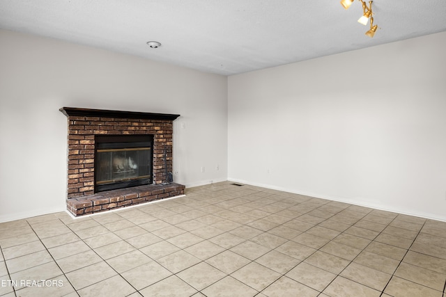 unfurnished living room with visible vents, a brick fireplace, and light tile patterned flooring