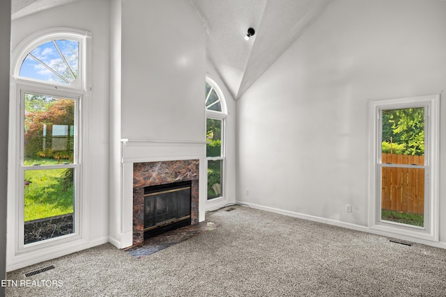unfurnished living room with visible vents, lofted ceiling, a high end fireplace, a textured ceiling, and carpet flooring
