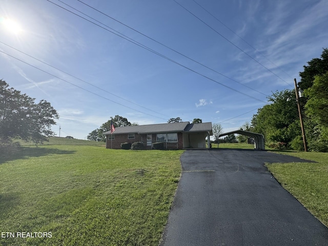 ranch-style home with brick siding, a front lawn, a detached carport, and aphalt driveway
