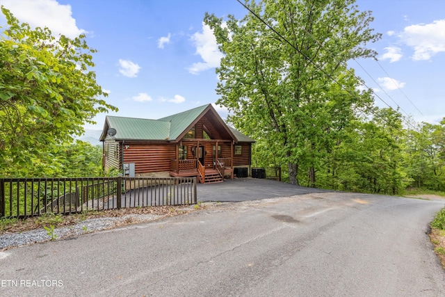 log cabin featuring log veneer siding, fence private yard, metal roof, and aphalt driveway