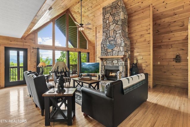 living room featuring a stone fireplace, wood walls, beam ceiling, and hardwood / wood-style flooring