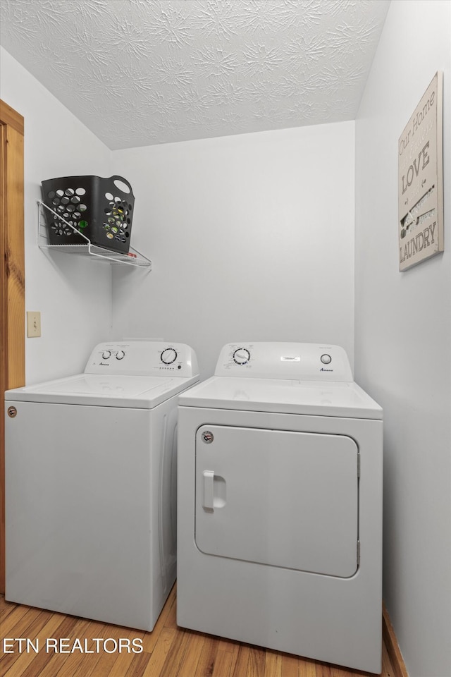 laundry room with laundry area, a textured ceiling, light wood-style flooring, and washing machine and clothes dryer