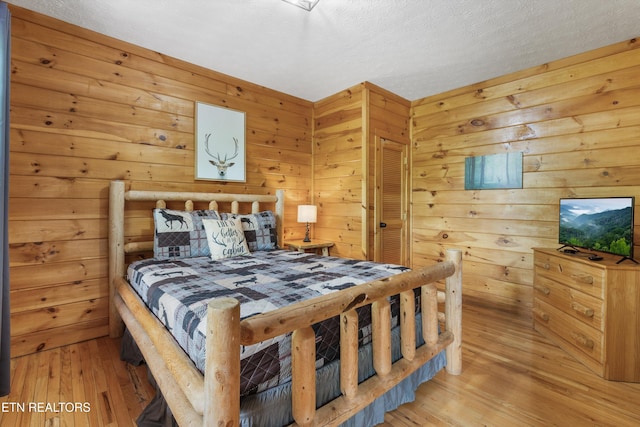 bedroom featuring light wood-style flooring and wooden walls