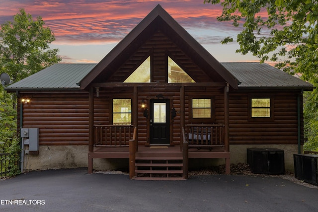 back of house with central AC unit, covered porch, and metal roof