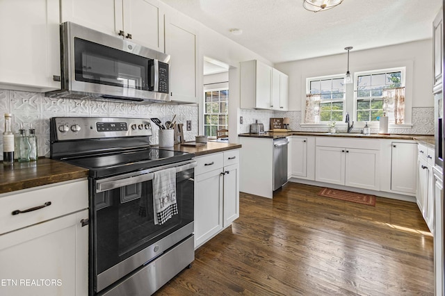 kitchen with plenty of natural light, decorative backsplash, stainless steel appliances, and white cabinetry