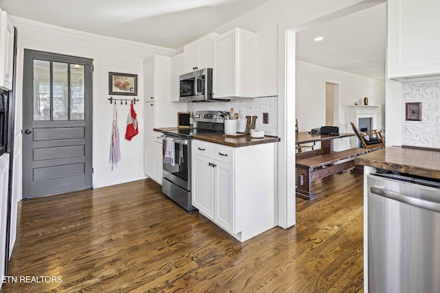 kitchen with dark wood-style flooring, white cabinets, and appliances with stainless steel finishes