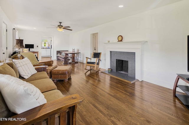 living room featuring a fireplace, ceiling fan, baseboards, and wood finished floors
