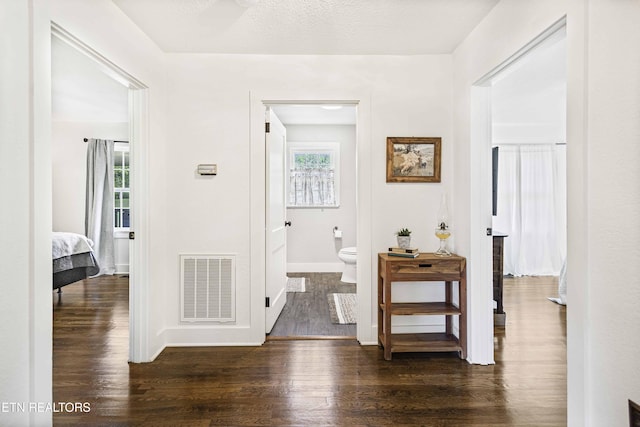 hall featuring plenty of natural light, visible vents, wood finished floors, and baseboards