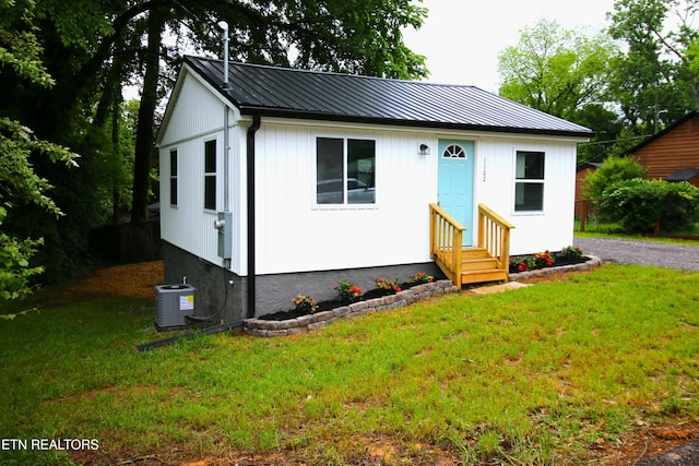 bungalow-style home with entry steps, central air condition unit, a front lawn, and metal roof