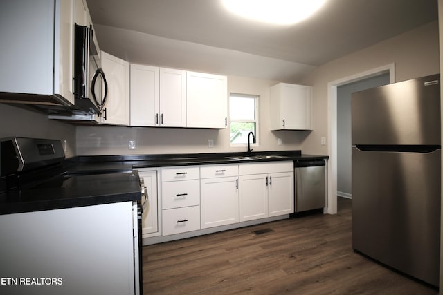 kitchen featuring dark countertops, a sink, stainless steel appliances, white cabinetry, and visible vents
