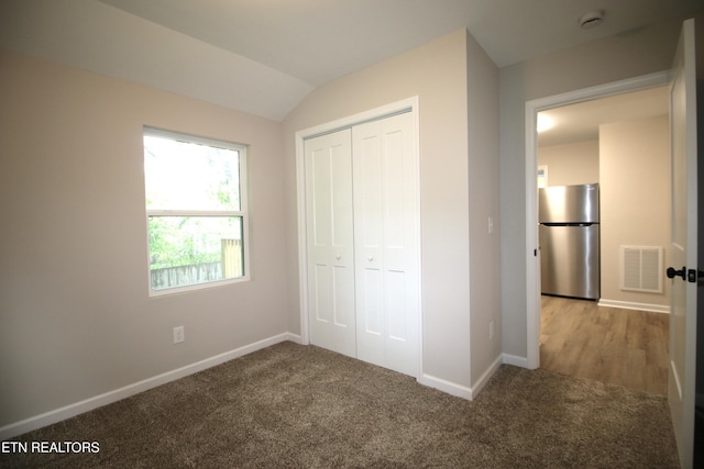 unfurnished bedroom featuring carpet, freestanding refrigerator, a closet, and visible vents