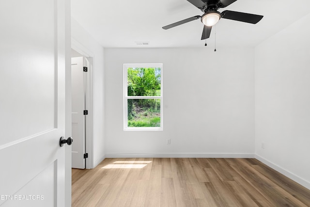 spare room featuring light wood-style floors, visible vents, baseboards, and a ceiling fan
