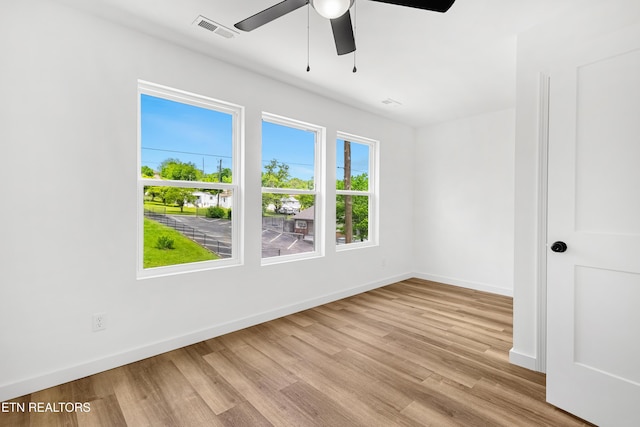 empty room featuring ceiling fan, baseboards, visible vents, and wood finished floors