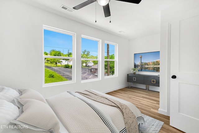 bedroom with baseboards, a ceiling fan, visible vents, and wood finished floors