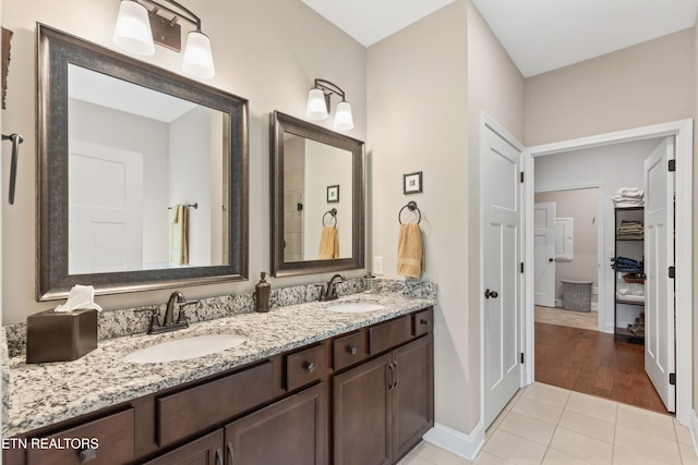 full bathroom with a sink, double vanity, baseboards, and tile patterned floors